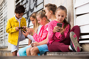 Group of children on their phones not worrying about cybercriminals