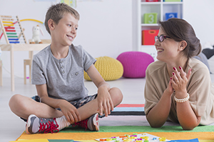 Teacher sat with young boy talking about their mental health policy