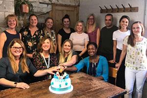 The Unravel team sat around table with cake