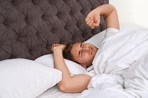 Male teacher waking up after only six hours of sleep