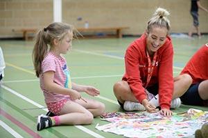 children in sports hall with staff to support key workers
