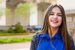 young girl smiling as schools urged to continue providing free period products