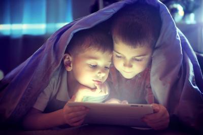 Two boys under a blanket watching an iPad