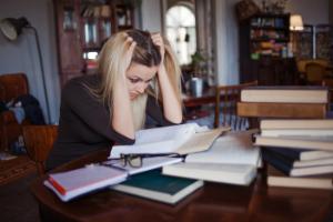 A teenage girl doing revision in front of a pile of books