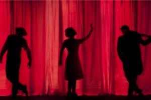 A silouhette of three actors on stage