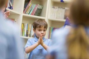 A little boy with his hands clasped