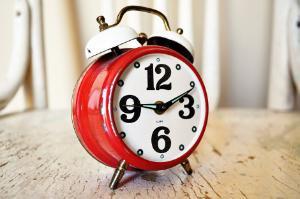 A red alarm clock showing the time of ten past nine