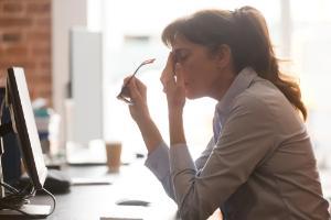 A woman at a computer rubbing her face