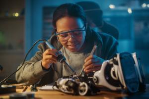 A young woman soldering some machinery