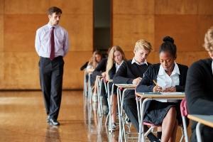 Pupils taking exams with a teacher walking among them
