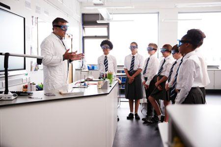 Male High School Tutor Teaching High School Students Wearing Uniforms In Science Class