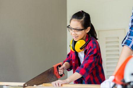 A child sawing a piece of wood