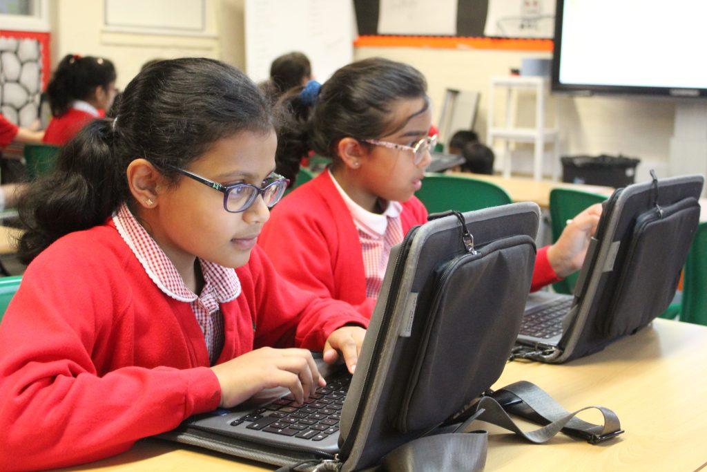 Two girls working on computers in class