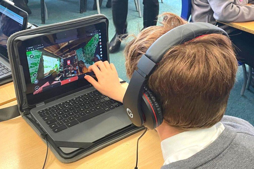 A boy wearing headphones working on a laptop